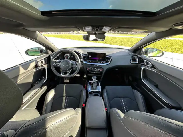 Modern Kia XCeed-interieur met panoramisch schuifdak, zwart lederen stoelen, touchscreen-display en een stuur met Kia-logo.