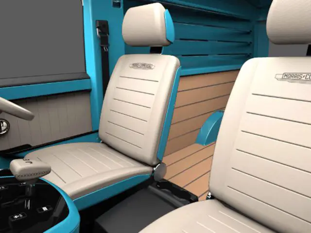 Interieur van een voertuig met twee beige stoelen met het opschrift 'Morris Commercial', een versnellingspook en een blauw en beige dashboard, dat het tijdloze ontwerp van de Morris JE weerspiegelt.