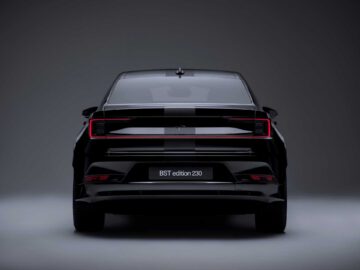 Achteraanzicht van een zwarte Polestar 2 BST edition 230, met strakke achterlichten en een modern design in een slecht verlichte omgeving.