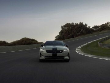 Een Polestar 2 BST edition 230 sedan rijdt op een bochtig racecircuit omgeven door groen en een bewolkte lucht.