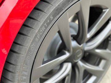 Close-up van de roodgeverfde wielkast en het donkere lichtmetalen velg van een Tesla Model S Plaid, uitgerust met een Michelin Pilot Sport 4S-band.