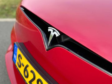 Close-up van de voorkant van een rode Tesla Model S Plaid met het Tesla-logo en een gedeeltelijk zicht op de kentekenplaat "S-629".