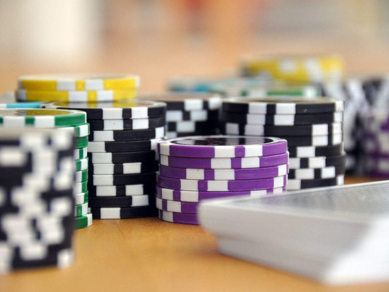Stapels veelkleurige pokerchips en een pak kaarten gerangschikt op een houten tafel, perfect voor een gokopstelling in de auto in je Tesla.