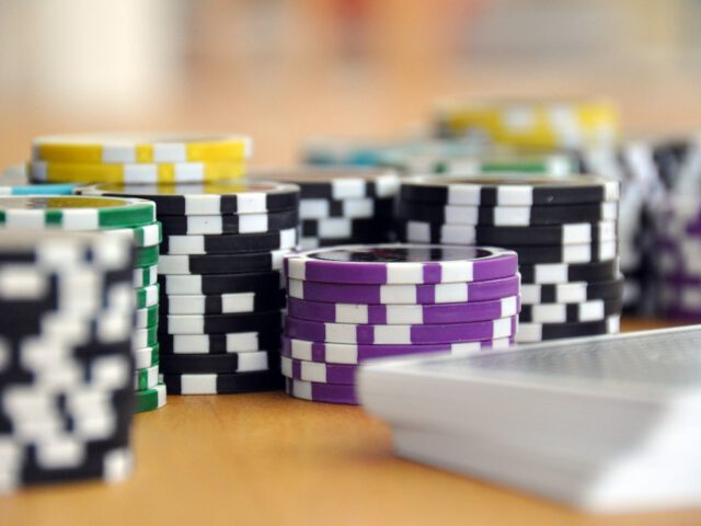 Stapels veelkleurige pokerchips en een pak kaarten gerangschikt op een houten tafel, perfect voor een gokopstelling in de auto in je Tesla.