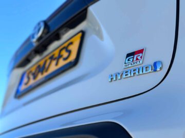 Close-up van de achterkant van een witte Toyota Yaris Cross GR Sport met een "GR Sport" -badge, een "HYBRID" -label en een gedeeltelijk zichtbare kentekenplaat met het nummer "84 7-FS".