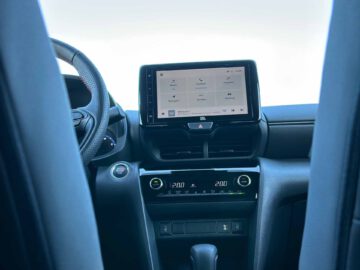 Weergave van het dashboard van een Toyota Yaris Cross GR Sport met een touchscreen-display met navigatie en andere opties, klimaatregelingsinstellingen, het stuur en de middenconsole.