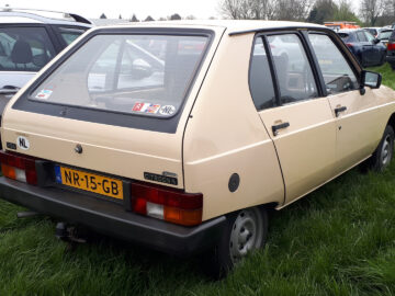 Een beige Citroën Visa met Nederlands kenteken, geparkeerd op het gras naast andere voertuigen.