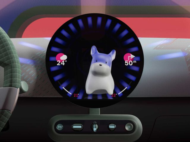 Een rond digitaal display in een auto toont een hondenavatar, met weersinformatie (24°C) en een afstandsindicator (50m) aan de zijkant. De bedieningselementen op het stuur en het dashboard zijn ook zichtbaar, geaccentueerd door de innovatieve MINI Spike-interface.