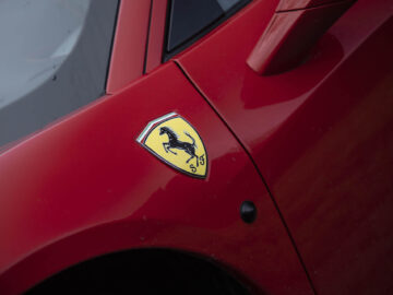 Een close-up van een rode Ferrari 458 Italia, met de nadruk op het iconische Ferrari-logo op het voorste zijpaneel.