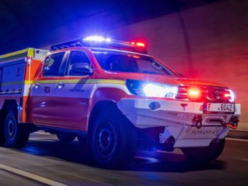 Een elektrische auto met knipperende rode en blauwe lichten rijdt door een tunnel en doet dienst als brandweer- en reddingsvoertuig.