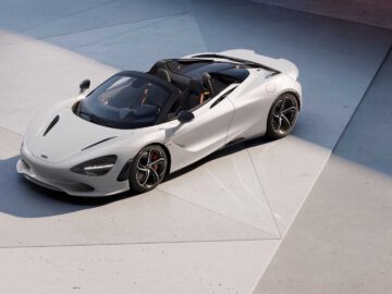 Een witte McLaren 750S cabrioletsportwagen staat geparkeerd op een lichtgekleurd, hoekig oppervlak met patronen. De auto heeft een aerodynamisch ontwerp met een strakke carrosserie en open bovenkant.