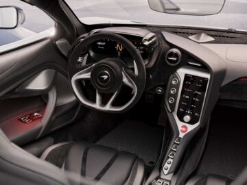 Binnenaanzicht van de McLaren 750S-sportwagen, met de nadruk op het stuur, het digitale dashboard en de centrale touchscreenbediening. Het ontwerp kenmerkt zich door strakke lijnen en een hightech console.