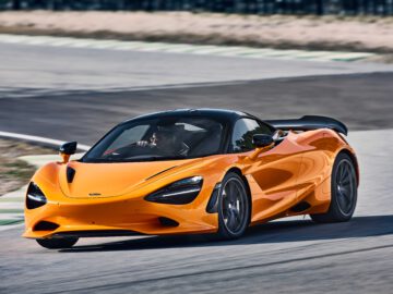 Een oogverblindende McLaren 750S in levendig oranje snelt moeiteloos over het circuit, waarbij precisietechniek en ongeremde kracht worden getoond.