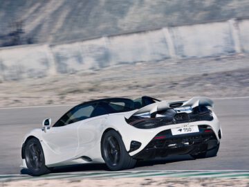 Een witte McLaren 750S-sportwagen met cabriokap rijdt op een circuit. De auto heeft het nummer 750LT op de achterste kentekenplaat en het landschap is dor met een betonnen barrière op de achtergrond.