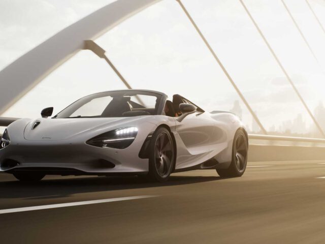 Een strak witte McLaren 750S rijdt onder een heldere hemel over een brug met gebogen bogen.