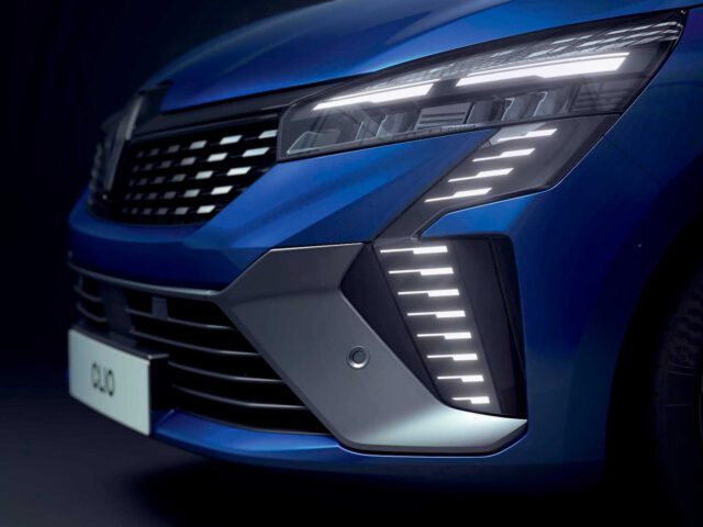 Close-up van de voorkant van een blauwe Renault Clio met moderne LED-koplampen, een strakke grille en een kentekenplaat met de tekst "DUO.