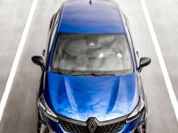 Bovenaanzicht van een blauwe Renault Clio die op een weg rijdt, gemarkeerd met een pijl en witte lijnen aan beide zijden.