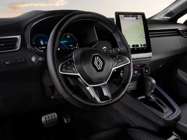 Binnenaanzicht van een moderne Renault Clio met een stuur met logo, digitaal dashboard, versnellingspook en een groot touchscreen met een kaart.