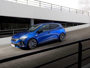 Een blauwe Renault Clio compacte auto geparkeerd op een hellende helling van een parkeergarage met meerdere niveaus op een bewolkte dag.