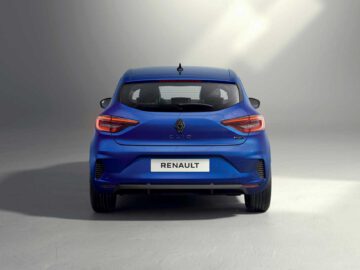 Achteraanzicht van een blauwe Renault Clio geparkeerd in een goed verlichte ruimte, waarbij de kenmerkende achterlichten en het prominente Renault-logo benadrukt worden.