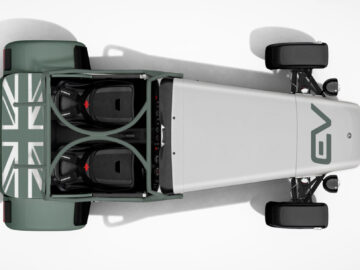 Bovenaanzicht van een minimalistische Caterham EV Seven met een open ontwerp, met een Union Jack-vlag aan de achterkant en de letters "GV" aan de voorkant. De auto beschikt over een strakke, gestroomlijnde carrosserie en zichtbare onderdelen van de voorwielophanging.