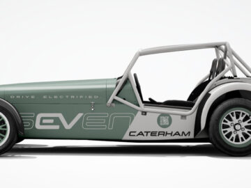 Zijaanzicht van een groen-witte Caterham EV Seven met de woorden "Drive. Electrified." en "Caterham" weergegeven op de zijkant. De auto heeft een minimalistisch ontwerp en een prominente rolbeugel.