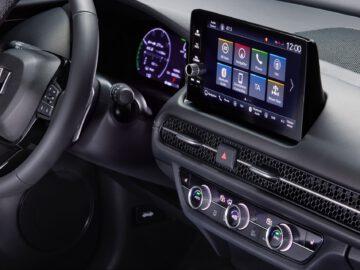 Het interieur van de Honda ZR-V toont een modern dashboard met een digitaal beeldscherm, een strak stuurwiel en verschillende bedieningsknoppen en draaiknoppen.