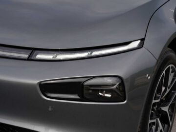 Close-up van een strak, modern XPeng-autofront met een donkergrijze carrosserie met een gestroomlijnd, smal koplampontwerp en een prominent onderste lichtcompartiment.