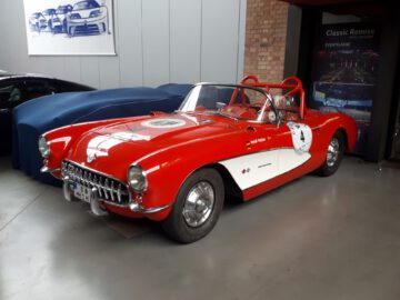 Een rood-witte klassieke sportwagen met nummer 4-embleem wordt binnenshuis tentoongesteld op Classic Remise, een tentoonstelling die bekend staat om zijn vintage auto-edelstenen.