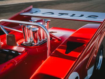 Close-up van een rode Lotus Type 66-raceauto, gericht op het achterste gedeelte en de prominente uitlaatpijpen.