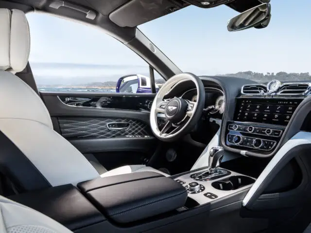 Binnenaanzicht van de Bentley Bentayga EWB Mulliner met een strak, modern dashboard, lederen stoelen, multifunctioneel stuur en groot centraal touchscreen-display.