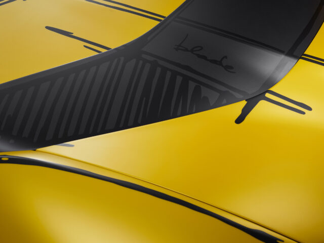 Een close-up van een gele Ferrari 812 Competizione-sportwagen met zwarte racestreepdetails en de handtekening van kunstenaar Blade op de achterruit.