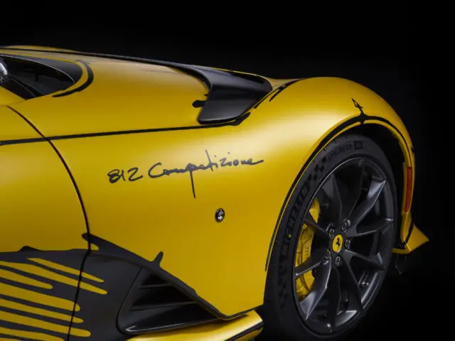 Close-up van het achterwiel en spatbord van een gele Ferrari 812 Competizione, met de tekst "812 Competizione.