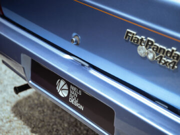 Close-up van de achterkant van een blauwe Fiat Panda 4x4 Piccolo Lusso met een Niels van Roij Design-badge.