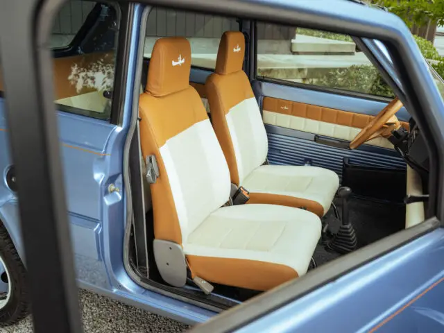 Binnenaanzicht van een vintage blauwe Fiat Panda 4x4 Piccolo Lusso met voorstoelen met een combinatie van bruine en witte bekleding.