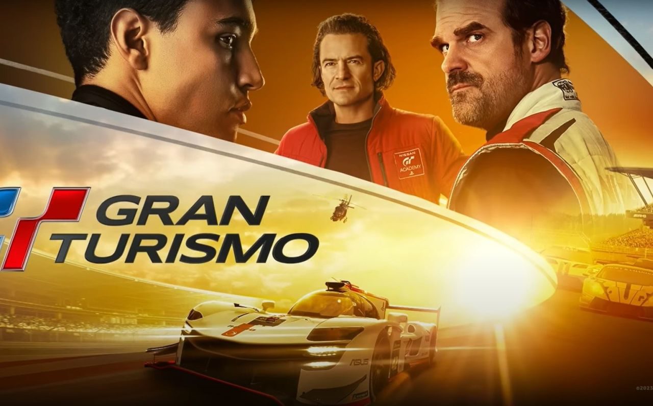 Promotieafbeelding voor "Gran Turismo" met drie mannen in racekleding met een raceauto en een Gran Turismo-circuit op de achtergrond.