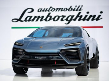 Een moderne Lamborghini Lanzador SUV wordt tentoongesteld voor een bord met de tekst "automobili Lamborghini" met de kleuren van de Italiaanse vlag eronder.