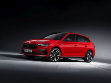 Een rode Skoda hatchback met strak design, zwart dak en lichtmetalen velgen, weergegeven op een donkere achtergrond.