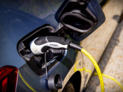 Close-up van een elektrische auto die wordt opgeladen via een oplaadkabel die is aangesloten op de oplaadpoort, net zoals u thuis uw eigen privélaadpaal zou gebruiken.