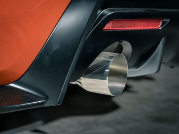 Close-up van de achterste uitlaatpijp en het achterlicht van een Toyota GR Supra GT4 100 Edition met een strakke, gepolijste metalen afwerking.