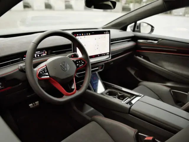 Het interieur van de Volkswagen ID.X Performance is voorzien van een modern auto-ontwerp met een digitaal dashboard, een groot centraal touchscreen-display met een kaart en lederen stoelen met rode stiksels. Op het stuur prijkt trots het logo van de autofabrikant.