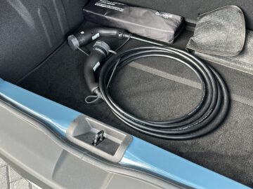 Het Dacia Spring Electric-voertuig beschikt over een handig opgeborgen oplaadkabel in de open kofferbak, waardoor de opgerolde lengte en de aansluitpunten goed uitkomen.