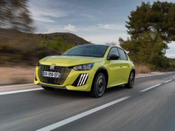 Een limoengroene Peugeot 208 die over een weg rijdt met bomen en heuvels op de achtergrond. De auto heeft een zichtbaar kenteken met de tekst "GS-066-EF.