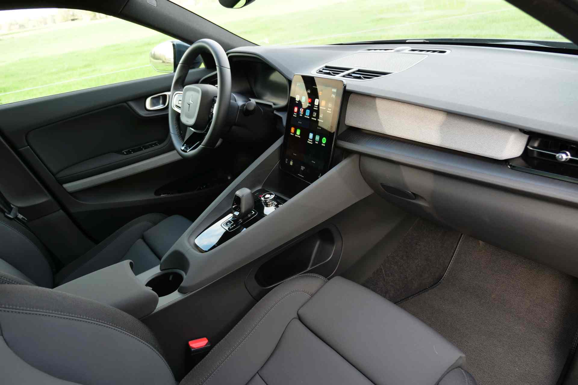 Modern auto-interieur met een strak dashboard met een groot aanraakscherm, minimalistische bedieningselementen en grijze bekleding: een ontwerp dat de verfijning van de Polestar-esthetiek weerspiegelt.