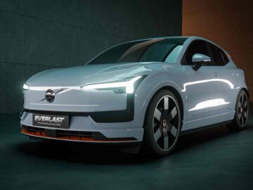 Een witte elektrische SUV, de EX30, staat geparkeerd in een slecht verlichte ruimte, met een strak, modern ontwerp en verlichte LED's aan de voorkant. Op het kenteken staat "EVERLAST.