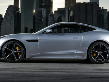 The Jaguar F-Type SVR is parked in front of a city skyline.