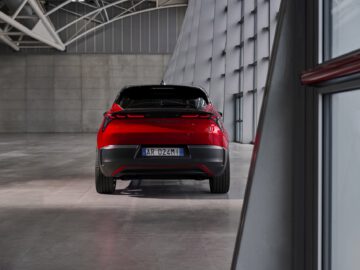 SUV eléctrico rojo de Alfa Romeo aparcado en un moderno edificio con elementos de diseño industrial.
