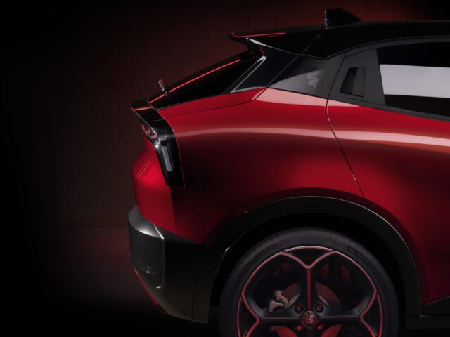 Rode Alfa Romeo MILANO-sportwagen in een donkere omgeving die het strakke ontwerp en de achterspoiler benadrukt.