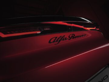 Detalle del emblema trasero y del diseño de las luces traseras de un vehículo Alfa Romeo Milano rojo.