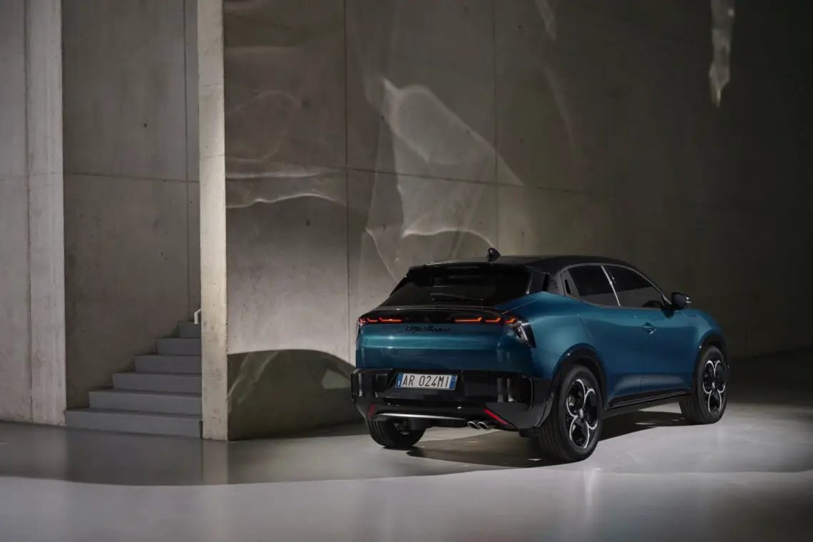 Een blauwe elektrische SUV van Alfa Romeo geparkeerd in een minimalistisch betonnen interieur met sfeerverlichting.